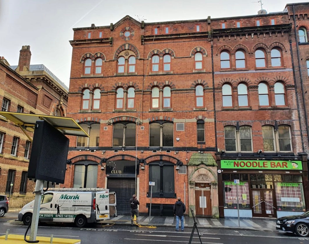 Monk Cleaning Services vans and team outside a red brick commercial building in Liverpool